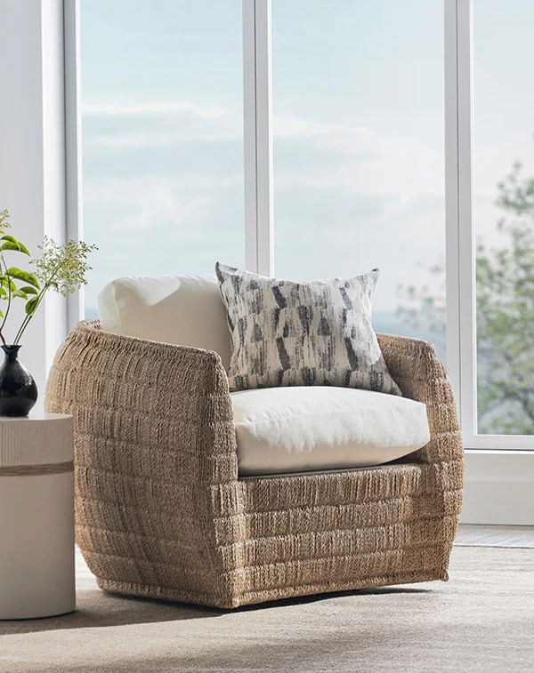 PALECEK — braided rattan lounge chair with white cushions beside a sunlit window